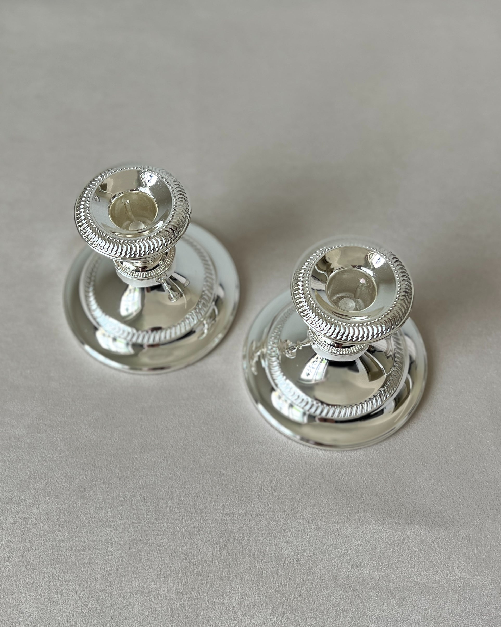 The pair of mid-century silver-plated candlesticks on a dining table or mantelpiece.
