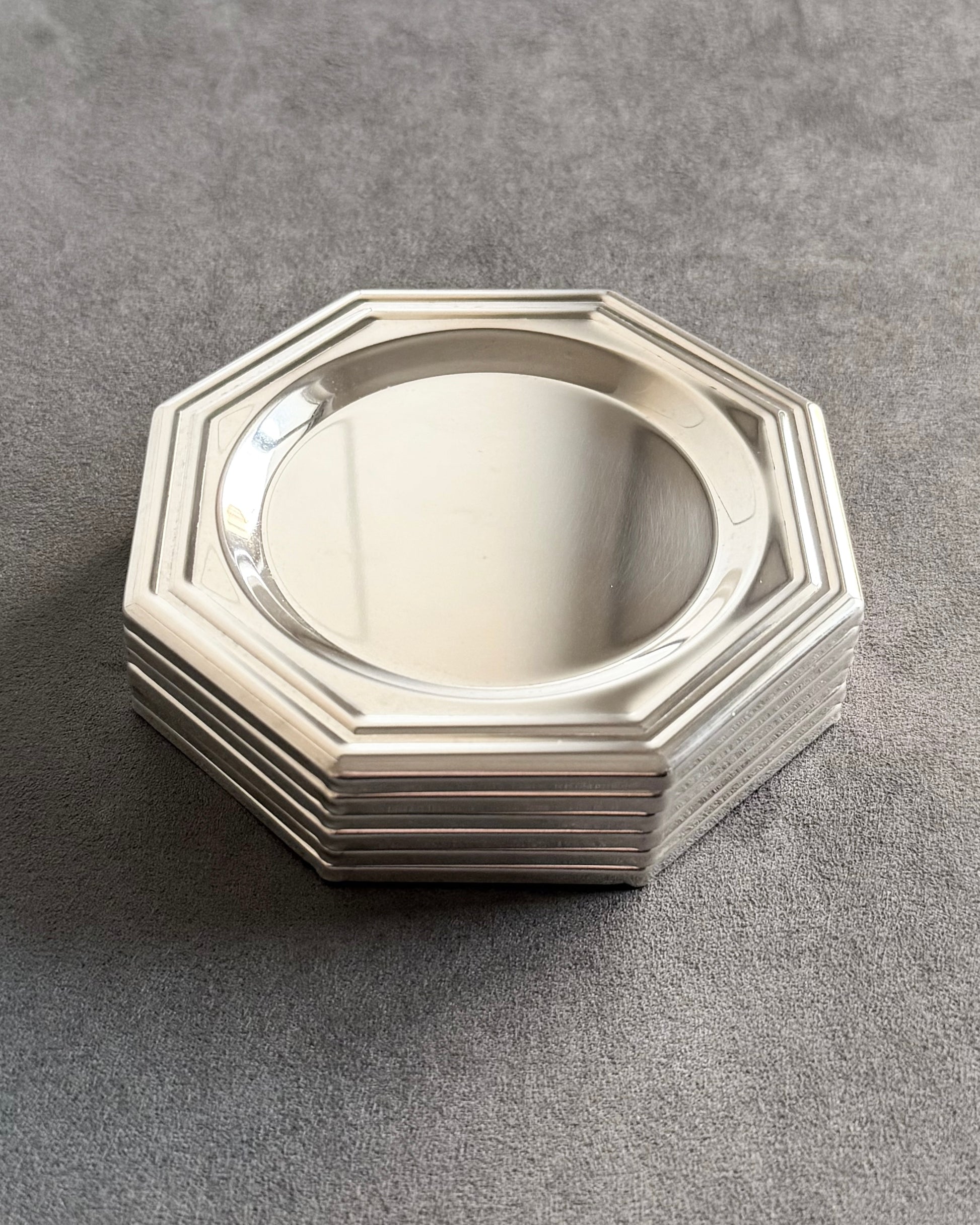 A stack of six minimalist silver-plated octagonal coasters, showing their slim profile—an ideal choice for a contemporary bar cart or as a sophisticated vintage gift.