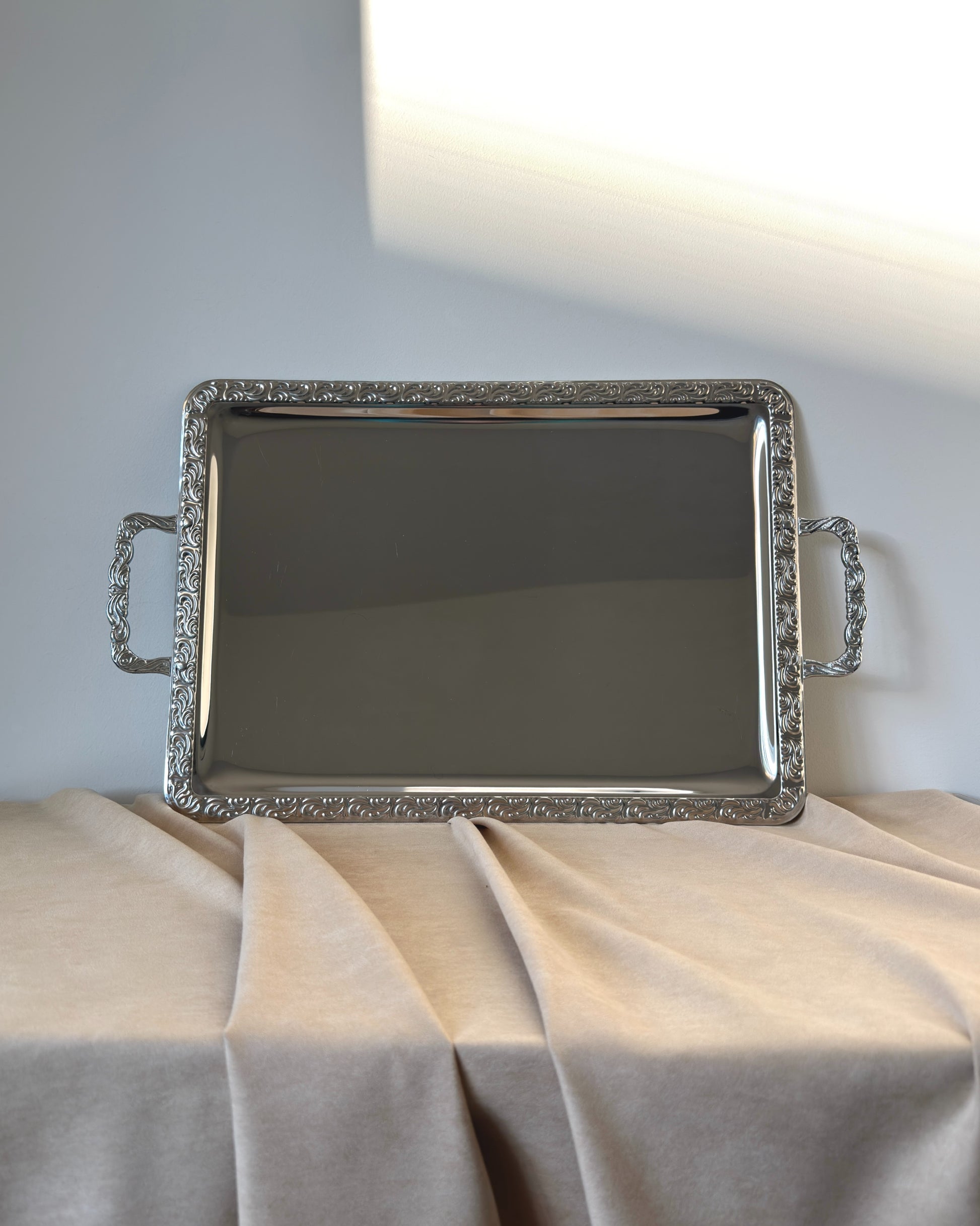 An extra-large vintage West German rectangular serving tray made of glossy stainless steel with decorative handles and a mirror-bright silver finish.